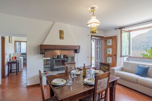 A dining area with a wooden table set for four, a sofa, and a view of the outdoors. - Casa Achille Pianello (Pianello del Lario)