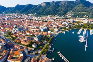 An aerial view of a city with a river, boats, and a prominent building with a dome. - Casa Achille Pianello (Pianello del Lario)