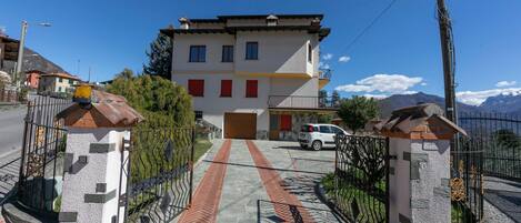 A two-story building with a red door, a paved driveway, and a gated entrance.