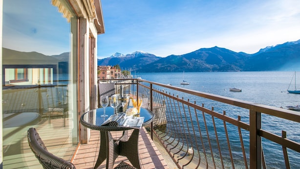 A balcony with a table and chairs, overlooking a lake with boats and mountains in the background. - Menaggio Tosca 2 in Menaggio (Menaggio)