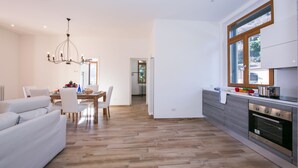 Eine moderne Küche mit Holzboden, einem Essbereich mit einer Chandelier und einem großen Fenster.