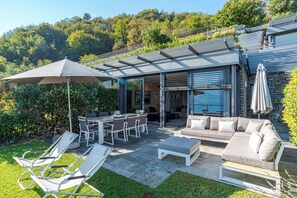 Une terrasse extérieure moderne comprenant un espace repas, des fauteuils et un canapé.