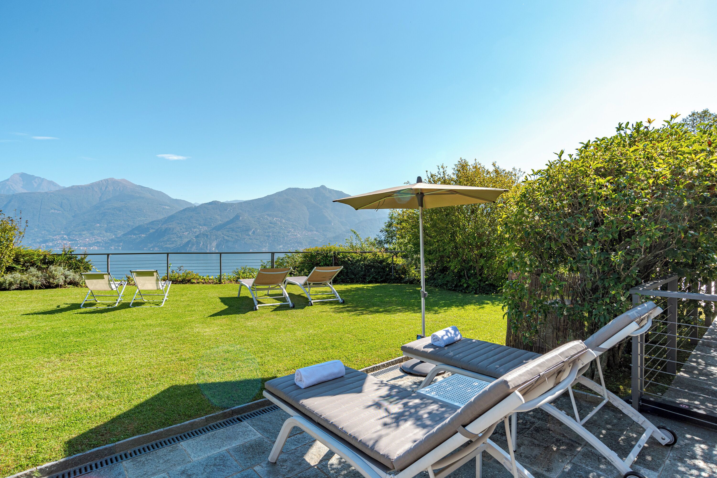 Un patio con poltrone e un tavolo, con vista su una montagna e un lago.