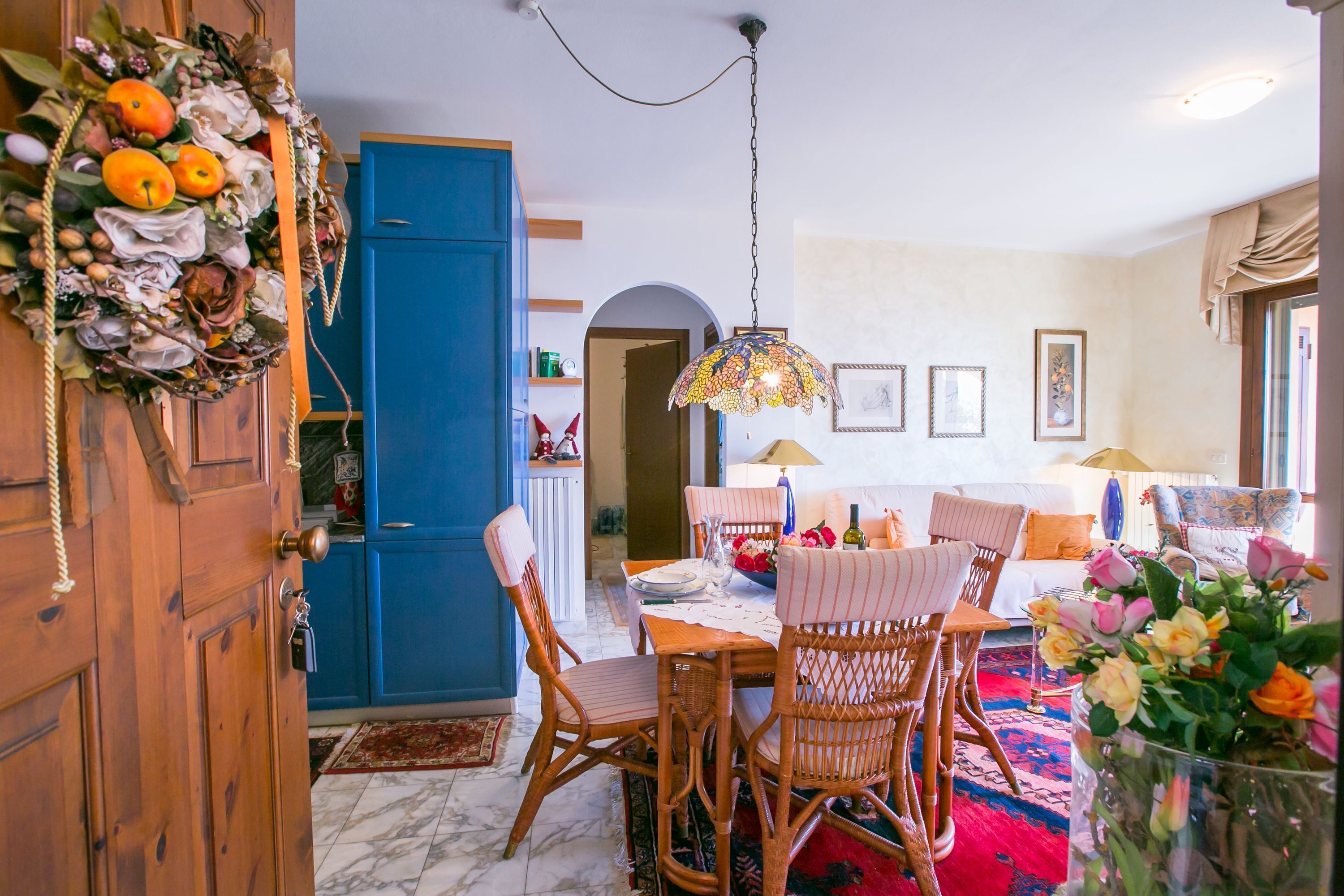 A dining area with a wooden table, wicker chairs, and a hanging light fixture.
