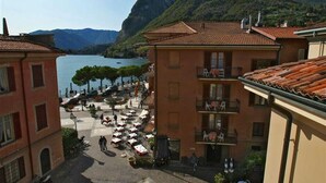 A building with a terrace overlooking a lake, with mountains in the background. - La Piazza Menaggio in Menaggio (Menaggio)