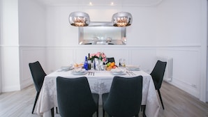 A dining area with a white table set for four, surrounded by black chairs. There are two pendant lights above the table, and a white radiator is visible on the wall to the right. - Menaggio Royale in Menaggio (Menaggio)