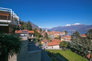 A hillside town with traditional buildings, a prominent church, and a mountain in the background. - Menaggio Royale in Menaggio (Menaggio)