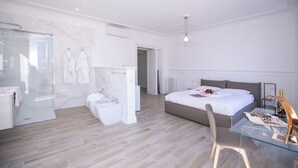 A modern bedroom with a glass desk, a large bed, a shower area, and a walk-in closet. - Menaggio Royale in Menaggio (Menaggio)