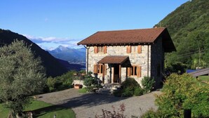 Ein Haus aus Stein mit rotem Dach, Holzläden und einer Steintreppe, die zum Eingang führt.