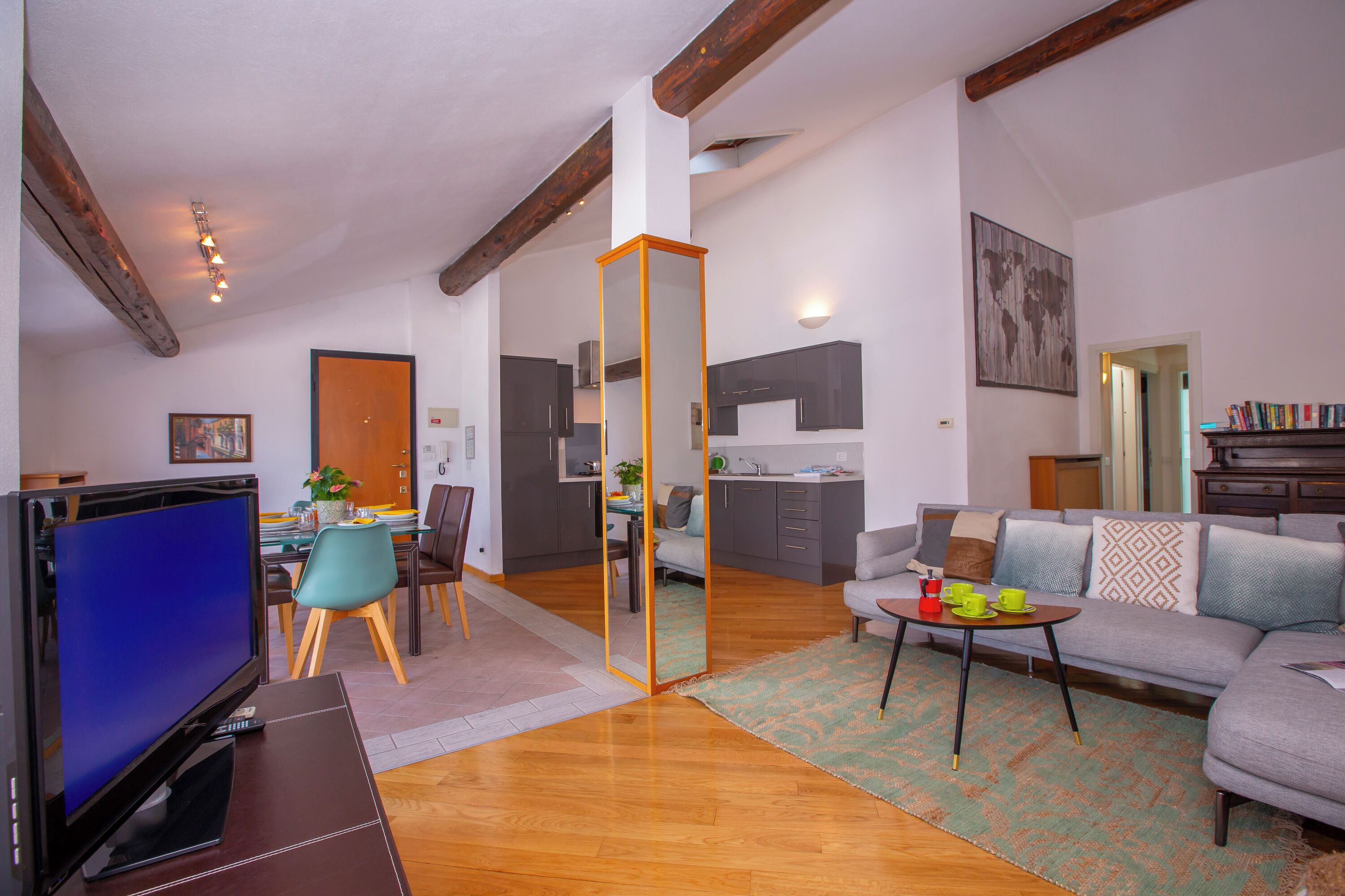 Ein modernes Wohnzimmer mit Fernseher, Sofa, Couchtisch und Essbereich.
