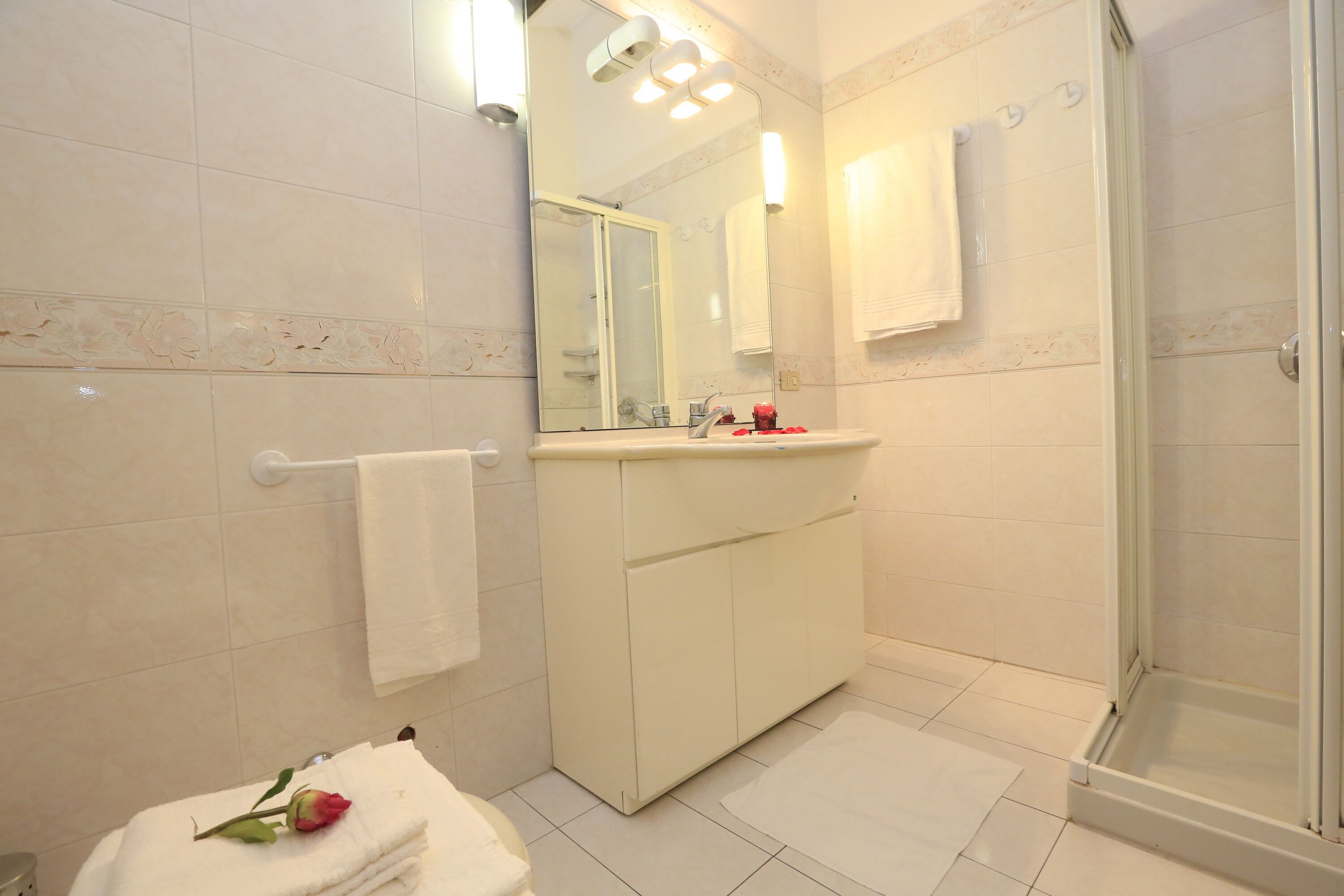Un baño con lavamanos blanco, espejo y ducha.