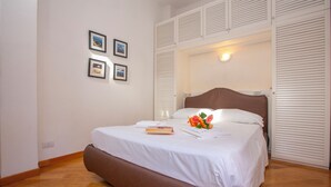 A neatly made bed with white linens, a brown headboard, and a single book and flower arrangement on the bed. - Bella Menaggio Panoramica (Menaggio)