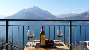 Una mesa con dos copas de vino y una botella, con vistas a un lago y montañas.