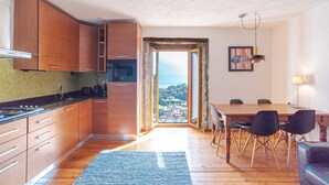 Une cuisine moderne avec des meubles en bois, un coin repas comprenant une table et des chaises, et une vue dégagée par une porte ouverte.