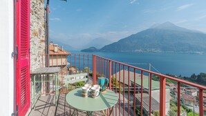 Un balcon avec une table et des chaises, donnant sur un lac et des montagnes.