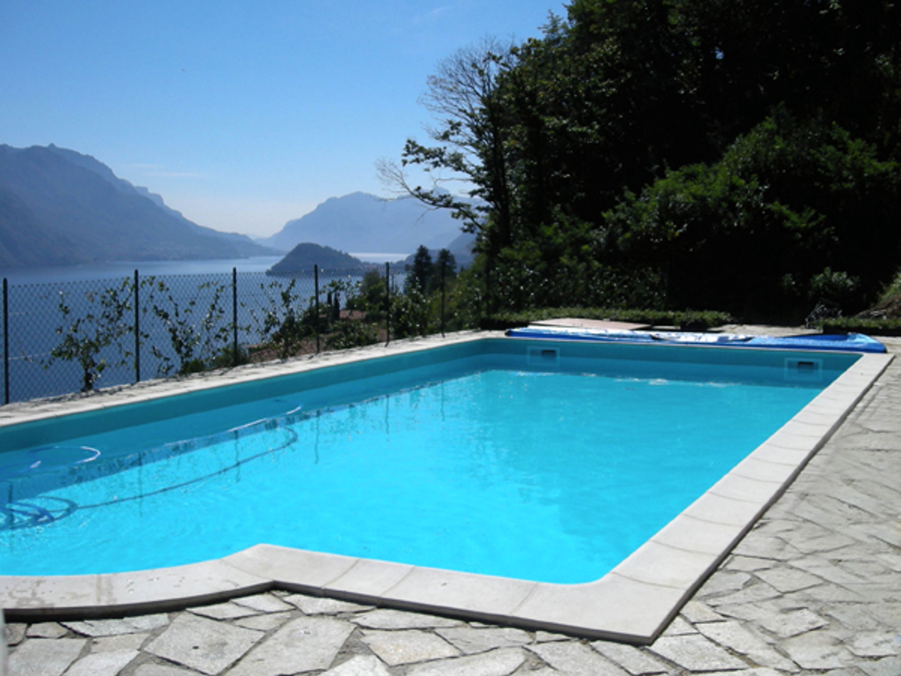 A rectangular swimming pool with a tiled edge, surrounded by a stone deck.