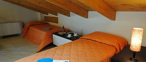 Un dormitorio con dos camas, una mesita de noche, una lámpara y una revista sobre la cama.