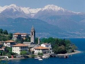 Un pueblo costero con una imponente torre de iglesia, edificios residenciales y barcos amarrados a lo largo del muelle.