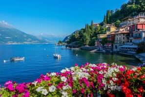 A lakeside town with colorful buildings, boats, and vibrant flowers.