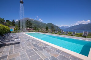 A swimming pool with lounge chairs and a water feature. - Sant Andrea Vista in Menaggio (Menaggio)
