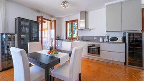 A modern kitchen with white cabinets, a dining table with chairs, and a built-in oven. - Bella Menaggio Terrazzo (Menaggio)