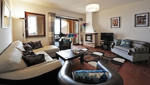 A living room with a sofa, armchair, coffee table, fireplace, television, and artwork on the walls. - Bellavista Grande in Menaggio (Menaggio)