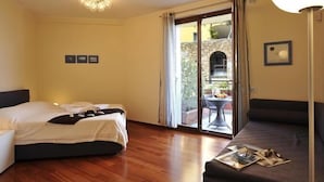 Habitación de hotel con cama, sofá, zona de comedor con mesa y sillas, y vistas al exterior.