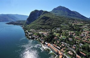 An aerial view of a coastal town with a marina, surrounded by mountains and a large body of water. - La Perla Di Sonenga - Giardino (Menaggio)