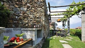 Pared de piedra con una parrilla y una mesa lista para comer al aire libre.