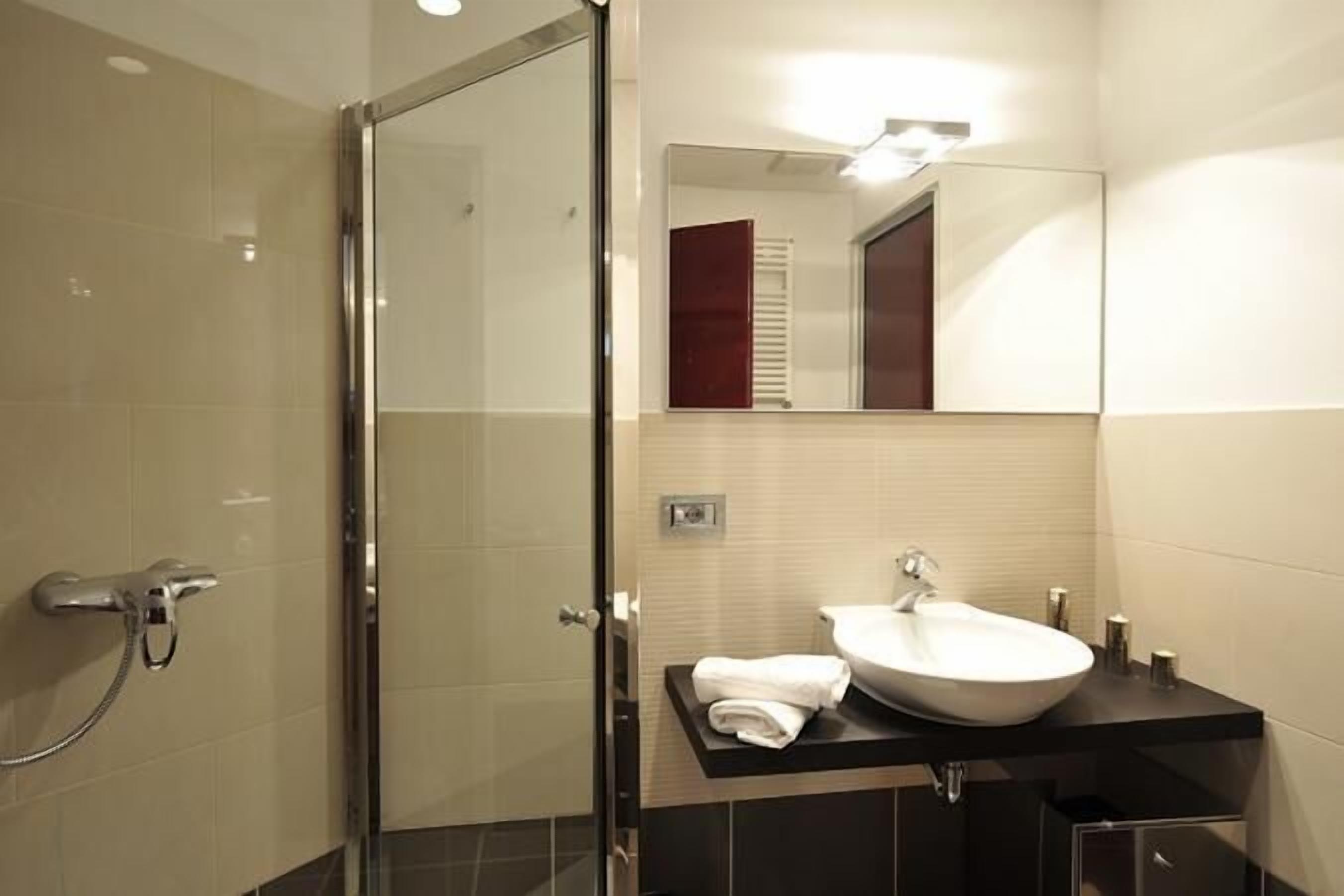 A modern bathroom with a glass shower enclosure, a white sink, and a mirror above the sink.