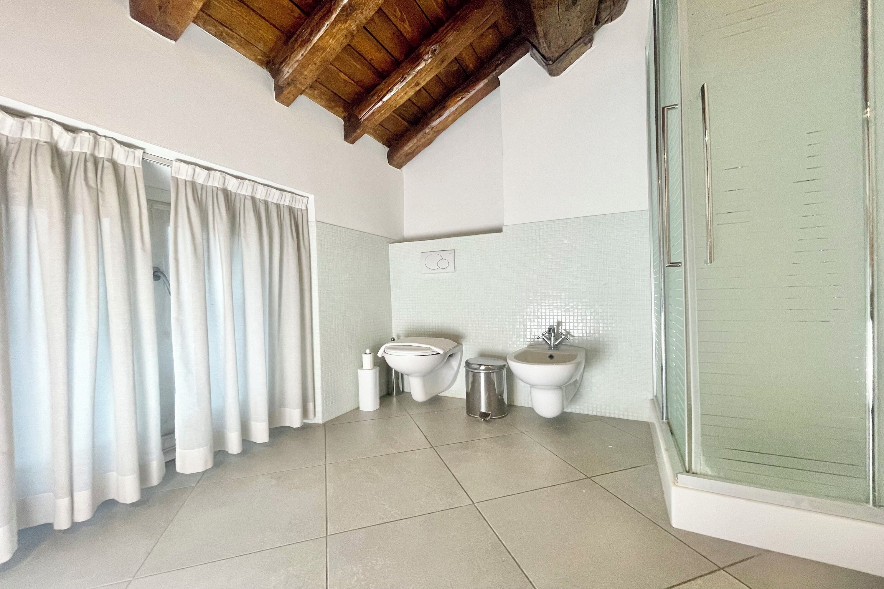 Une salle de bain équipée d’une douche, de toilettes, d’un bidet et d’une poubelle.