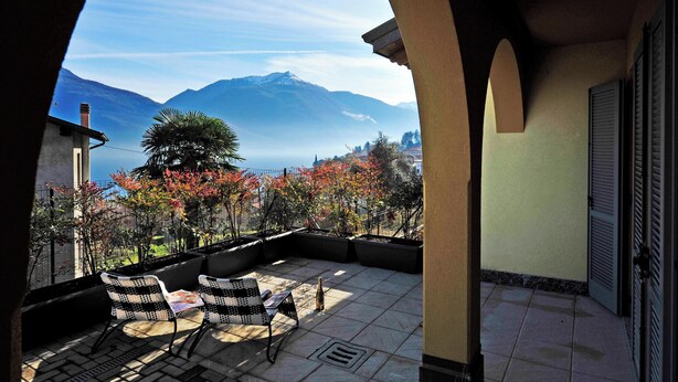 Un balcon avec deux chaises, une table et une vue sur les montagnes et les arbres.
