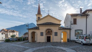 Une église dotée d’un clocher, d’un pavement circulaire en pierre et, en arrière-plan, d’une montagne.