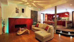 A modern living room with a sofa, a fireplace, and a kitchen in the background. - Villa Bianca - Grande (Menaggio)