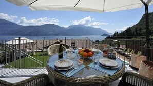 An outdoor dining area with a table set for two, overlooking a mountainous landscape and a body of water. - Villa Bianca - Grande (Menaggio)