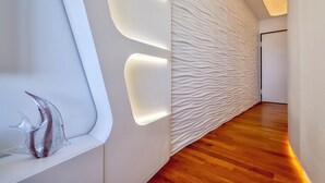 Un interior moderno con suelo de madera, pared texturizada y una escultura de vidrio.
