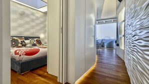 Un dormitorio moderno con cama, mesita de noche y vista al mar a través de un amplio ventanal.