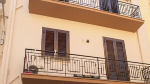 A two-story building with balconies, a bicycle parked in front, and a door with a sign. - "Cozy Central Apartment, Near the Sea - Ideal for Holidays" (Balestrate)