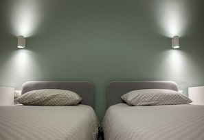 Une chambre avec deux lits, chacun étant équipé d’un oreiller et d’une table de chevet.