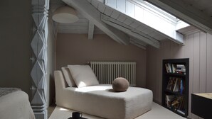 Una camera da letto in stile loft con soffitto spiovente, una libreria a muro e un'ampia finestra che lascia entrare la luce naturale.