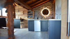 Una cucina con travi in legno, una parete in pietra e un forno a incasso.