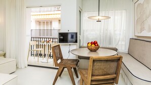 A modern living room with a round table, two wicker chairs, a sofa, a TV, and a fruit bowl.