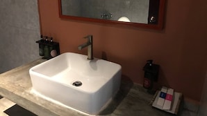Une salle de bain avec un lavabo blanc, un miroir et un distributeur de savon.