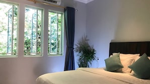 Une chambre à coucher avec un lit, une plante en pot et une fenêtre avec des rideaux.