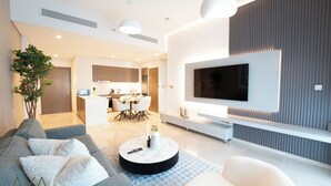 Een moderne woonkamer met een bank, salontafel en een aan de muur bevestigde televisie.