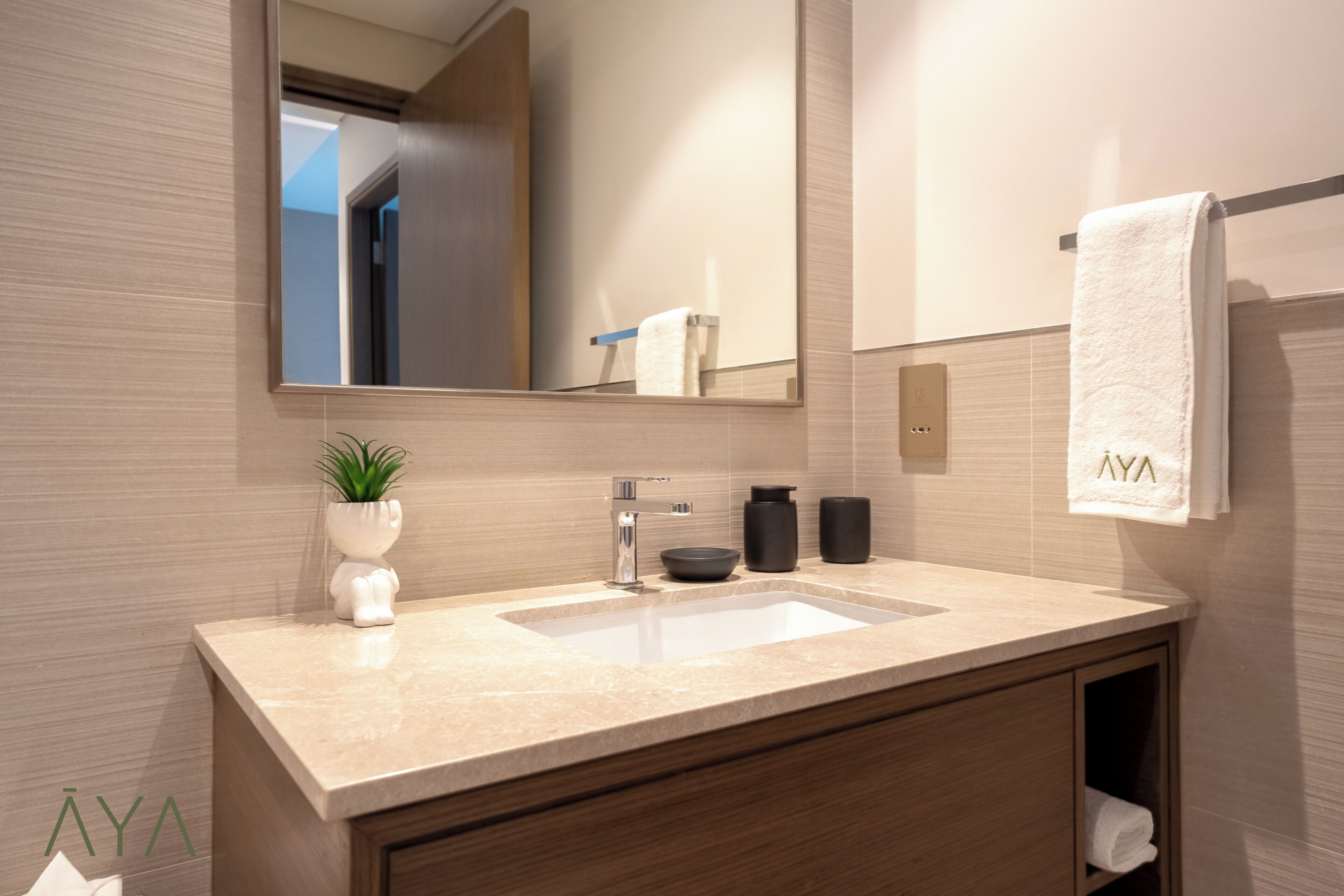A modern bathroom with a large mirror, a sink, and a towel rack.