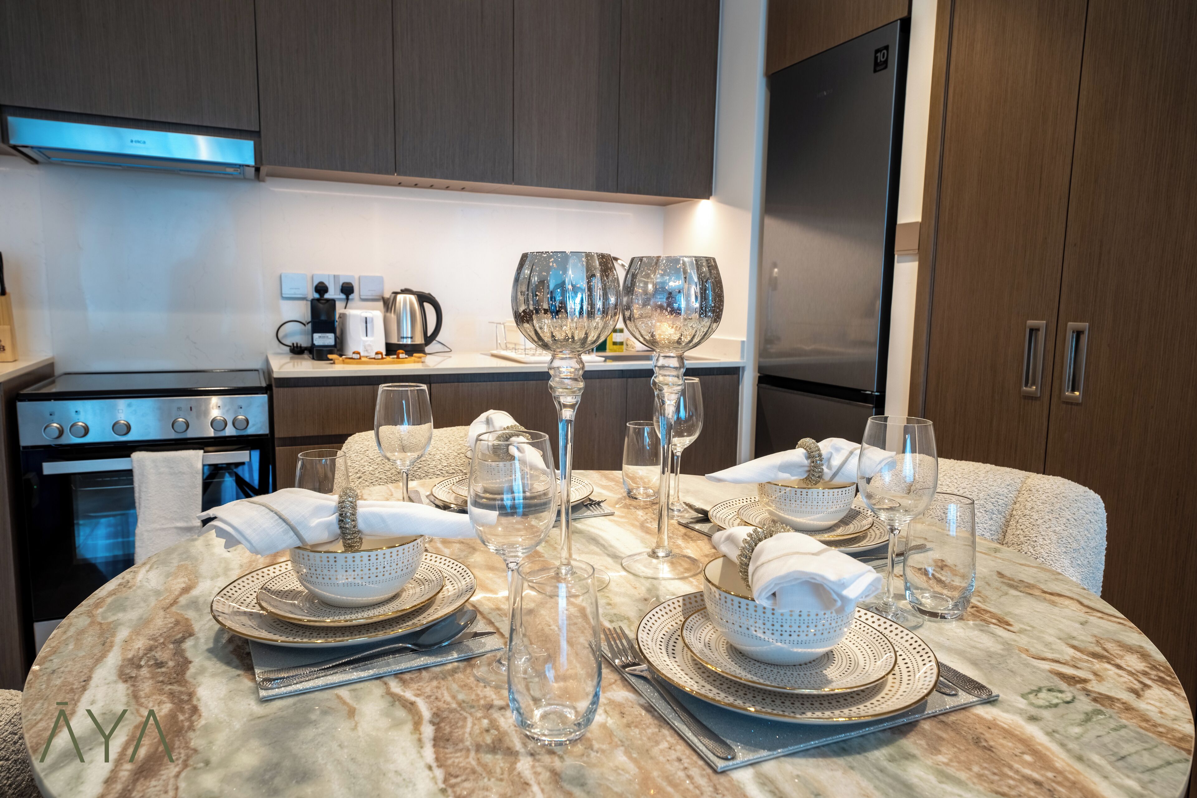 Una cocina moderna con encimera de mármol, electrodomésticos de acero inoxidable y un comedor listo para una comida.