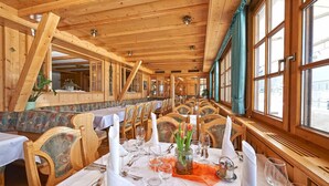 A restaurant with wooden interiors, long tables, and chairs.