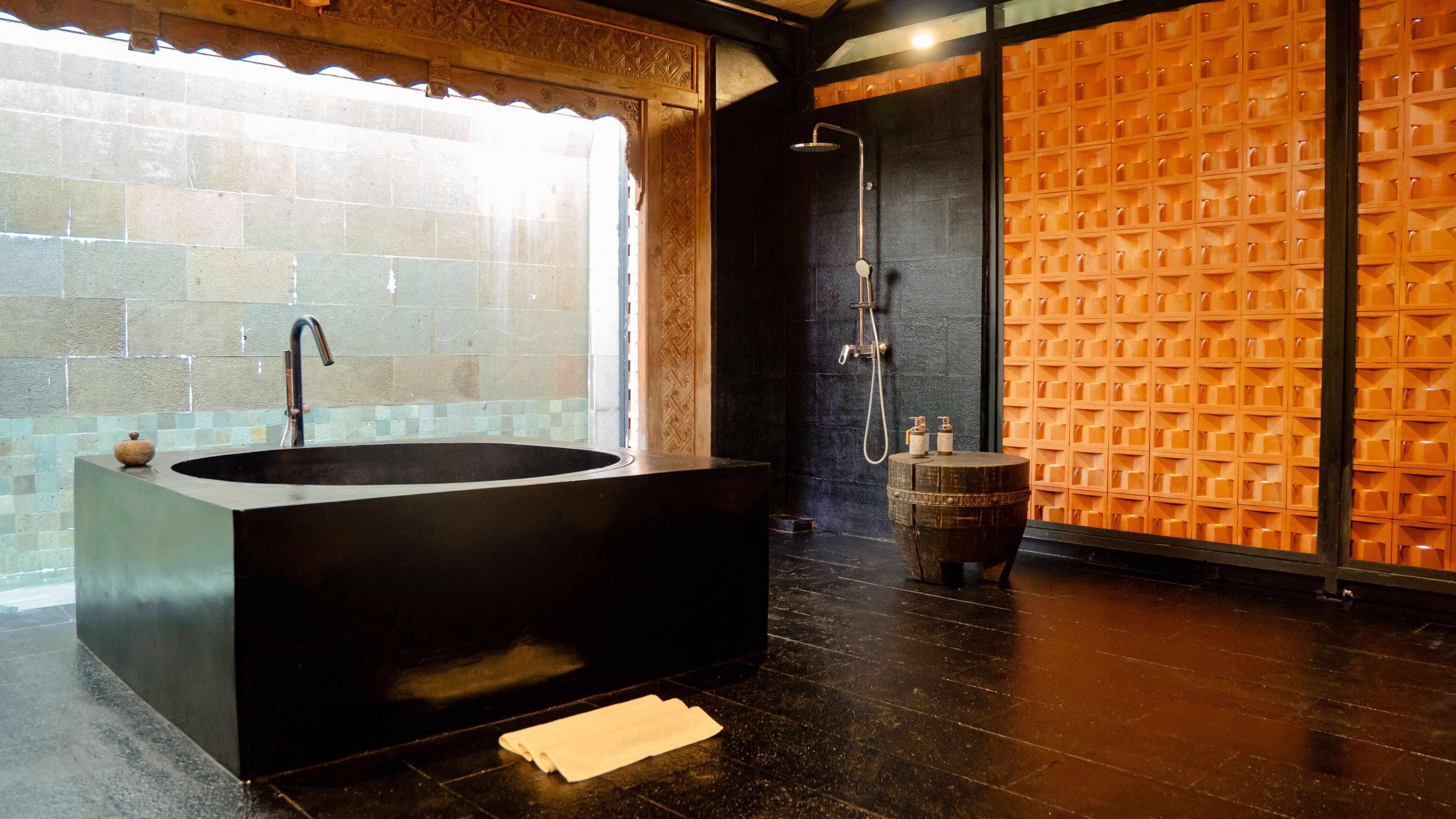 Une salle de bain moderne avec une baignoire sur pieds, une douche et un tabouret en bois.