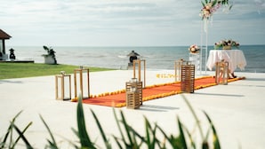 A beachside wedding setup with a white table, chairs, and a floral arrangement. - Seaside Oceana Resort by Mahaprana (Kubutambahan)